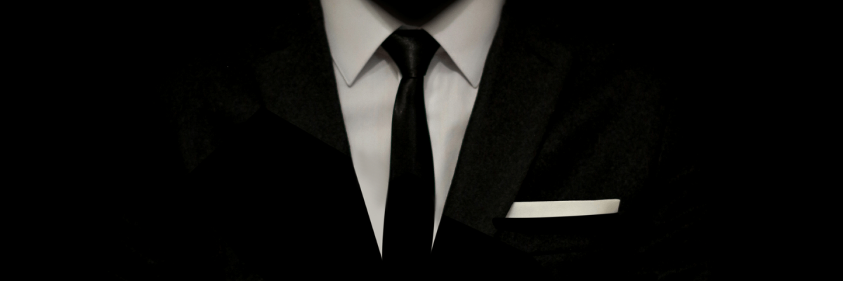 Black suit with white shirt and pocket square blending in with black background