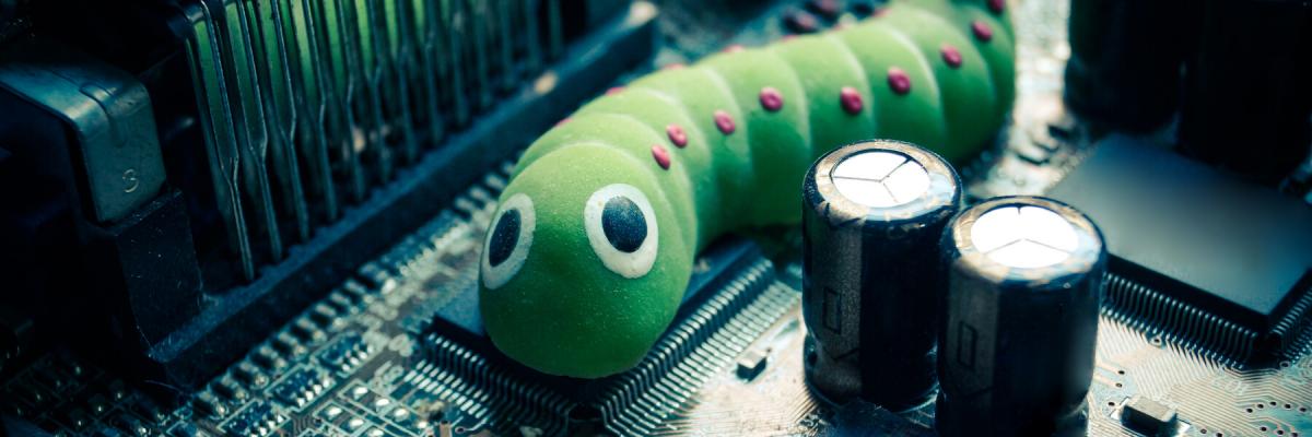 Green worm with pink dots and big eyes on a computers motherboard 