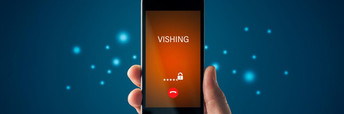 Hand holding smart phone with vishing calling with a blue background behind phone and hand